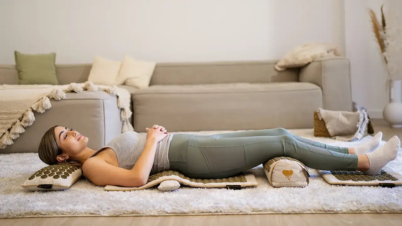 Eine Frau liegt auf einer Akupressurmatte - Akupressurmatten von CALM ELEPHANT bieten Premium-Qualität - hypoallergen und aus natürlichen Materialien
